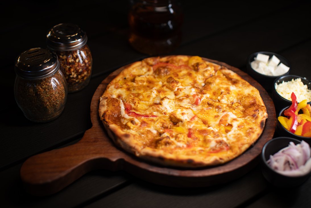 Pizza being topped with cheese